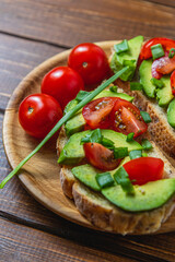 Avocado toast topped with tomato and green onion on a slice of carrot bread