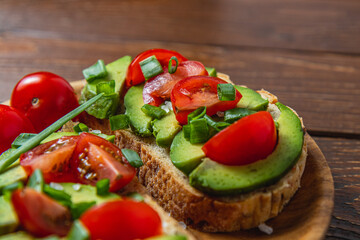 Avocado toast topped with tomato and green onion on a slice of carrot bread