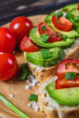 Avocado toast topped with tomato and green onion on a slice of carrot bread