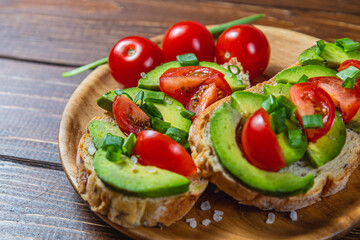 Avocado toast topped with tomato and green onion on a slice of carrot bread