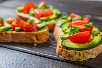 Avocado toast topped with tomato and green onion on a slice of carrot bread