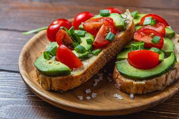 Avocado toast topped with tomato and green onion on a slice of carrot bread