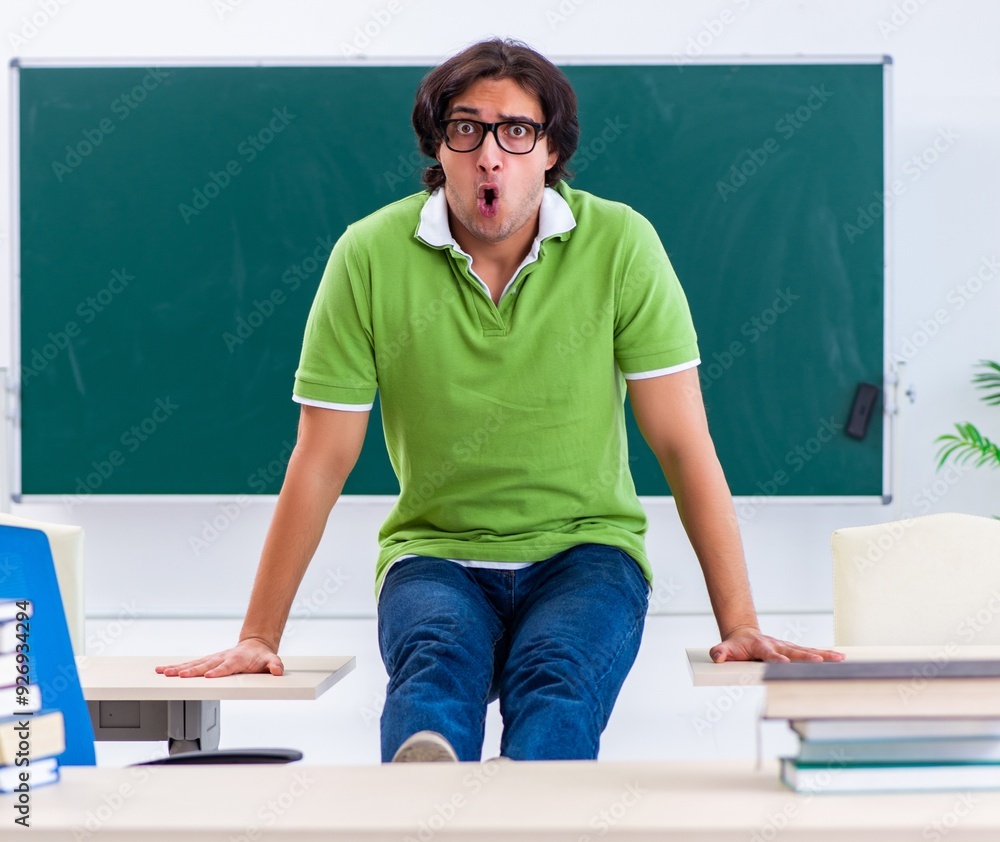 Wall mural young student doing physical exercises in the classroom