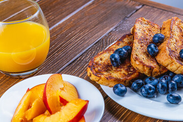 French toast on a plate with blueberries, orange juice, nectarine for breakfast