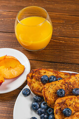 French toast on a plate with blueberries, orange juice, nectarine for breakfast