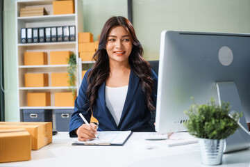 A young Asian businesswoman sits at her table, watching the computer screen.She analyzes, plans,...