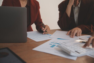 Group of confident business people point to graphs and charts to analyze market data, balance sheet, account, net profit to plan new sales strategies to increase production capacity.