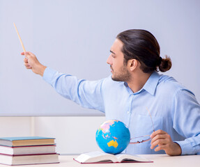 Young male geography teacher in front of whiteboard