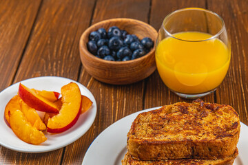 French toast on a plate with blueberries, orange juice, nectarine for breakfast