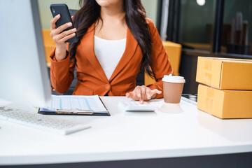 A young Asian businesswoman sits at her table, watching the computer screen.She analyzes, plans,...