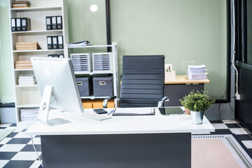 A desk in the office is neatly organized with a computer monitor, document, tablet, and telephone placed on it. The setup is ready for efficient work and smooth communication.