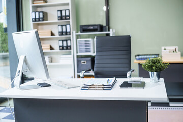 A desk in the office is neatly organized with a computer monitor, document, tablet, and telephone placed on it. The setup is ready for efficient work and smooth communication.