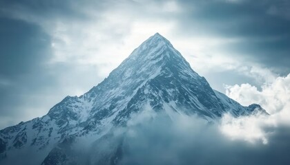 Snowy mountain peak reaching for the sky with clouds above.