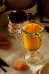 Sea Buckthorn Tea with Rosemary in Glass Mug on Rustic Background