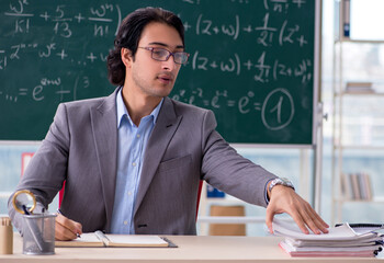 Young handsome math teacher in classroom