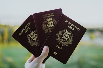 three red Estonian passports for travel against a background of nature