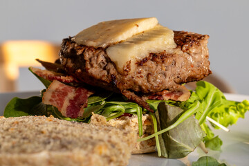 An open-faced home-made bacon cheeseburger with salad.
