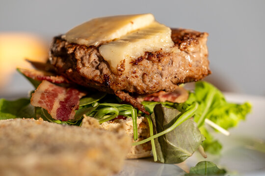 An open-faced home-made bacon cheeseburger with salad.