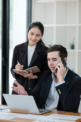A man and a woman are talking on a cell phone in a business setting
