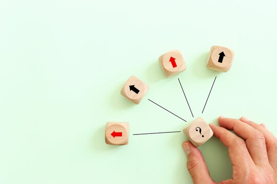 Wooden cubes with question marks and arrows on a pastel background