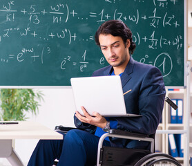 Young handsome man in wheelchair in front of chalkboard