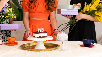 Birthday celebration featuring small cake with candles, presents, and flowers