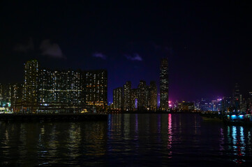 Naklejka premium The night view of Hong Kong Island from the Kowloon. Hong Kong cityscape and seascape at night. Nature and city scene.