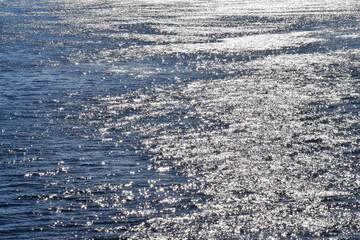 Close-up of the sea, calm water, on the sunny day. Shinny wave pattern, wave texture. Sea background. Nature concept.