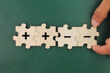 wooden puzzle with positive and negative symbols. a combination of positive and negative charges....