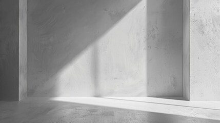 A bright beam of sunlight shines through a large window and casts a long shadow across the floor of a modern concrete room. The walls are smooth and white, with a minimalist aesthetic.