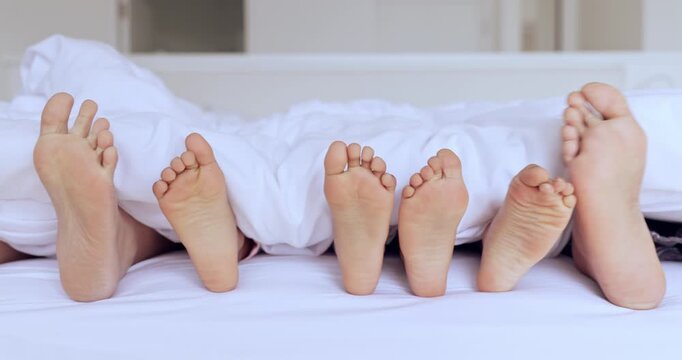 Family, bed and feet together in closeup, kids and play in home with sheet, hospitality or comfort with bonding. People, children and bedroom with toes, blanket and sole to relax, holiday or vacation