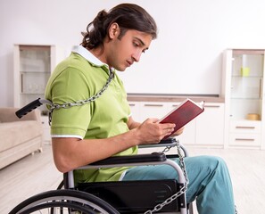 Young male invalid in wheel-chair suffering at home