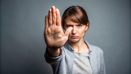 A person raising their hand in a stop gesture to communicate the concept of stopping something, stop, halt, cease, prevent, end