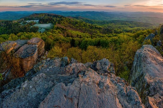 View from the rocks of a beautiful mountain landscape with hills, forests and a frozen meadow during sunrise.