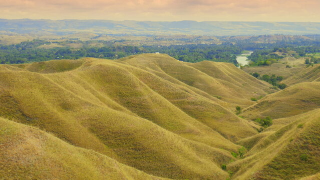 Landschaft nahe Waingapu in Sumba Indonesien mit braunen grasigen Bergen in der Trockenzeit