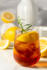 Iced tea with ice, rosemary and lemon slices on the white table.