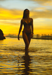 Fototapeta premium Image of woman standing on sandy beach with slight waves Mountains and fjords, travel to Krabi, Thailand, famous places, vacation, travel to Asia, take photos under the evening sun in summer.