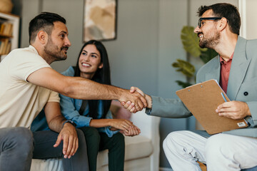 Young couple shaking hands deal contract real estate investment business agreement agent handshake...