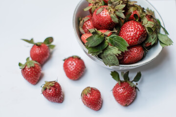 Heap of fresh strawberries in white ceramic bowl on rustic white background, fresh fruits.