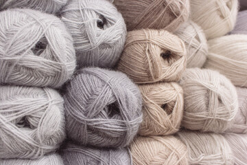Grey and beige balls of yarn in storage. Warm wool yarn background. Knitting hobby. Row of grey and beige yarn. Handiwork store. Knit background. Handcraft concept. Knit pattern.