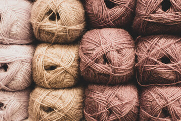 Beige and brown balls of yarn in storage. Warm wool yarn background. Knitting hobby. Row of brown...