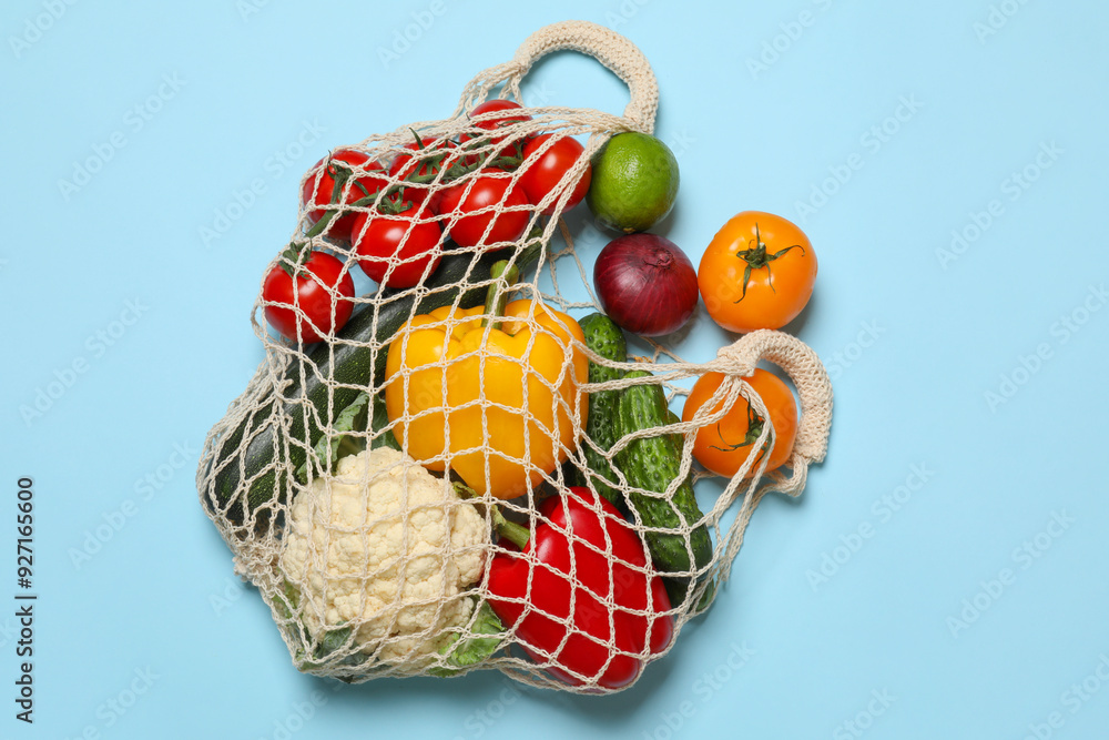 Sticker Delivery of vegetarian products. String bag with different vegetables and fruit on light blue background, top view