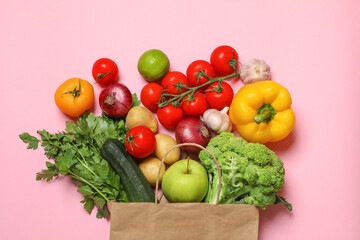 Delivery of vegetarian products. Paper bag with different vegetables and fruits on pink background, top view