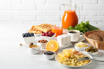 Tasty breakfast. Scrambled eggs, ham, cheese and other food served on light table