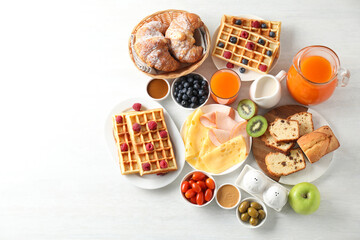 Different meals served for breakfast on white table, flat lay