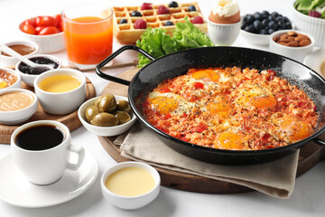 Cup of coffee and different meals served for breakfast on white table