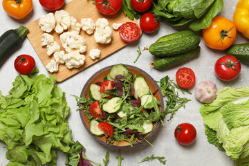 Healthy vegetarian food. Salad in bowl and vegetables on grey textured table, flat lay