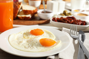 Tasty breakfast. Fried eggs, orange juice and cutlery on table, closeup