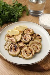 Tasty grilled courgette slices with lemon on wooden table