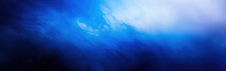 Obraz premium An abstract image with soft, blue and white swirls, fading into a blurred background. The image is reminiscent of water or smoke, creating a sense of movement and depth.